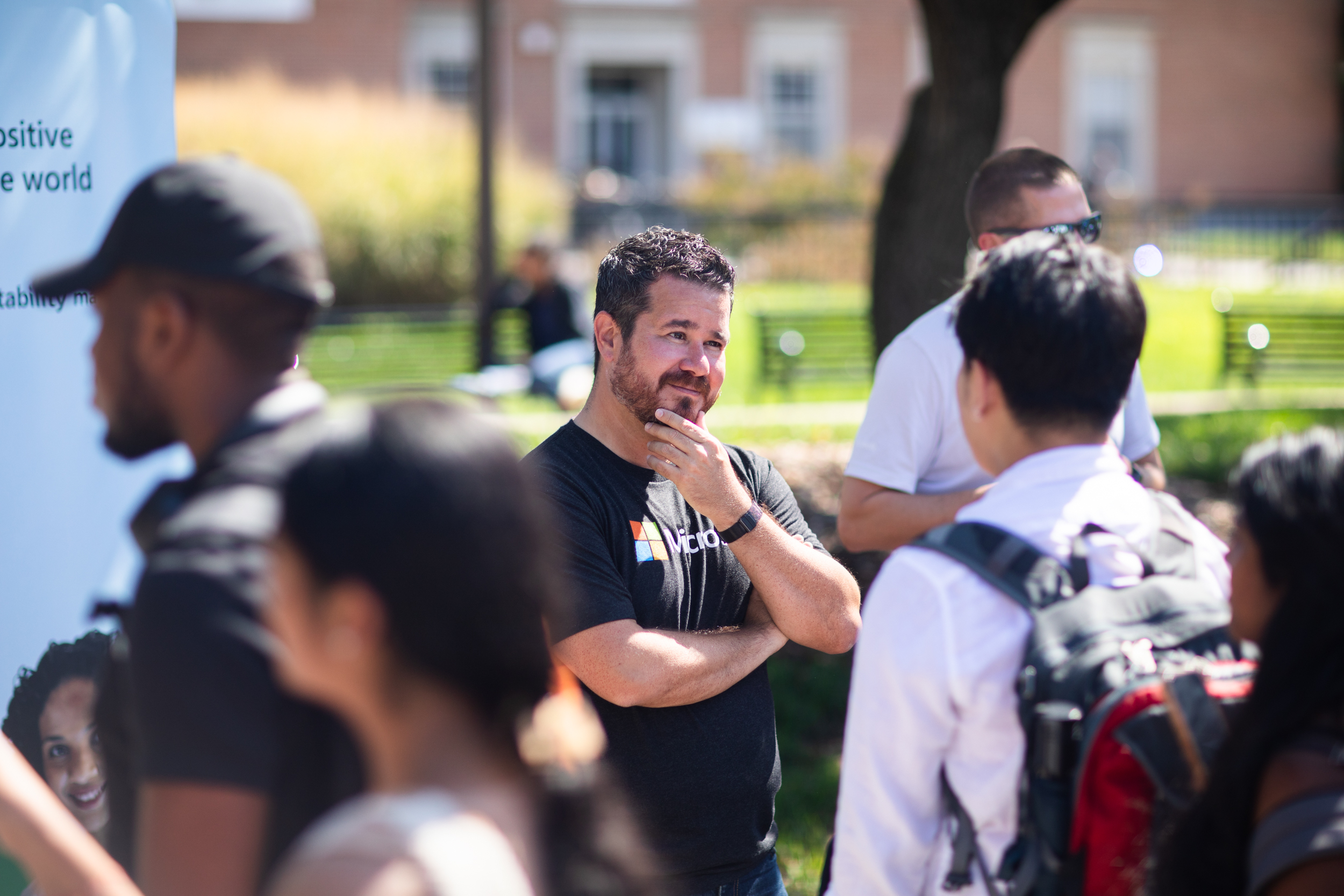 Man wearing a Microsoft T-shirt speaking with students at Tech Block Party