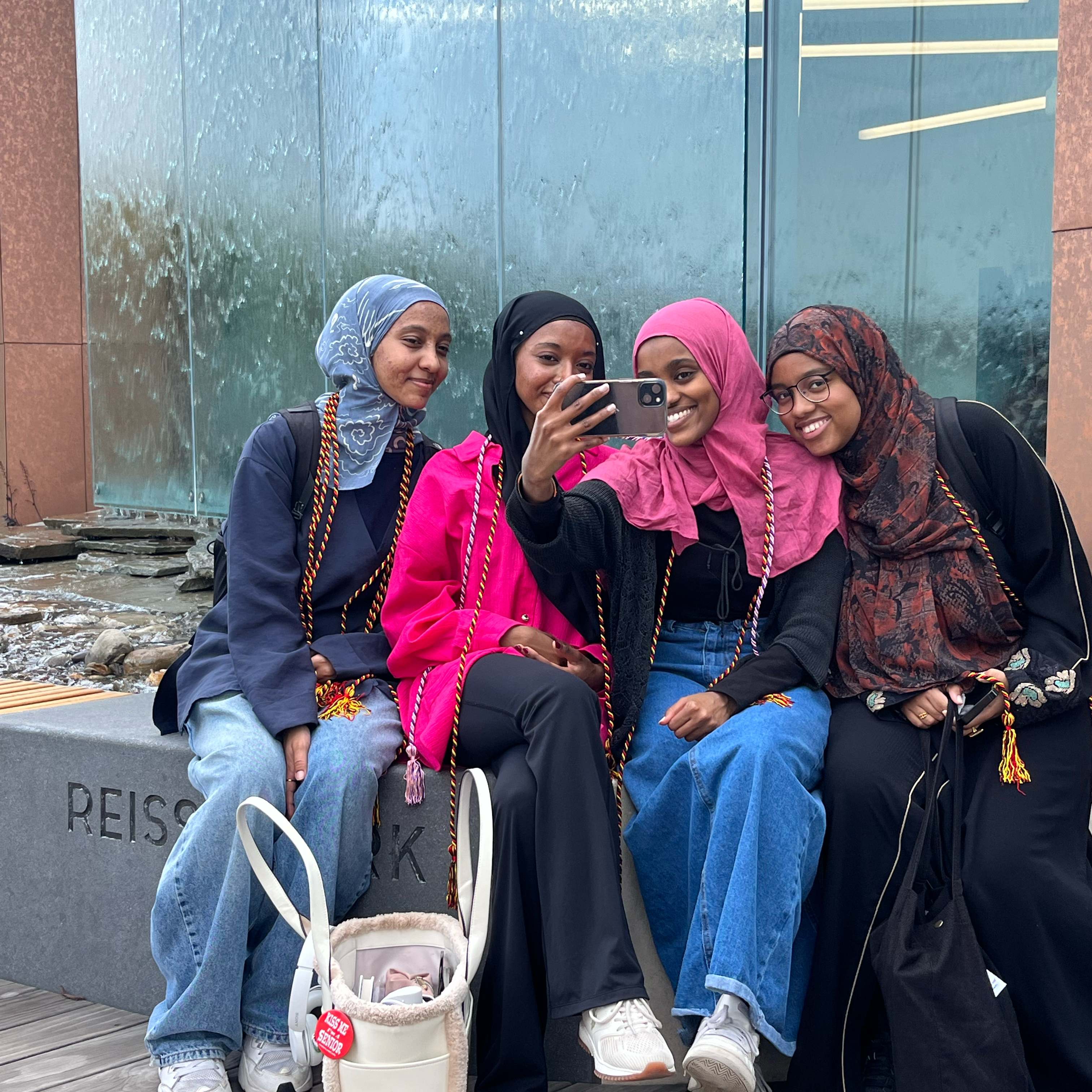 A group of students takes a selfie while wearing graduation cords