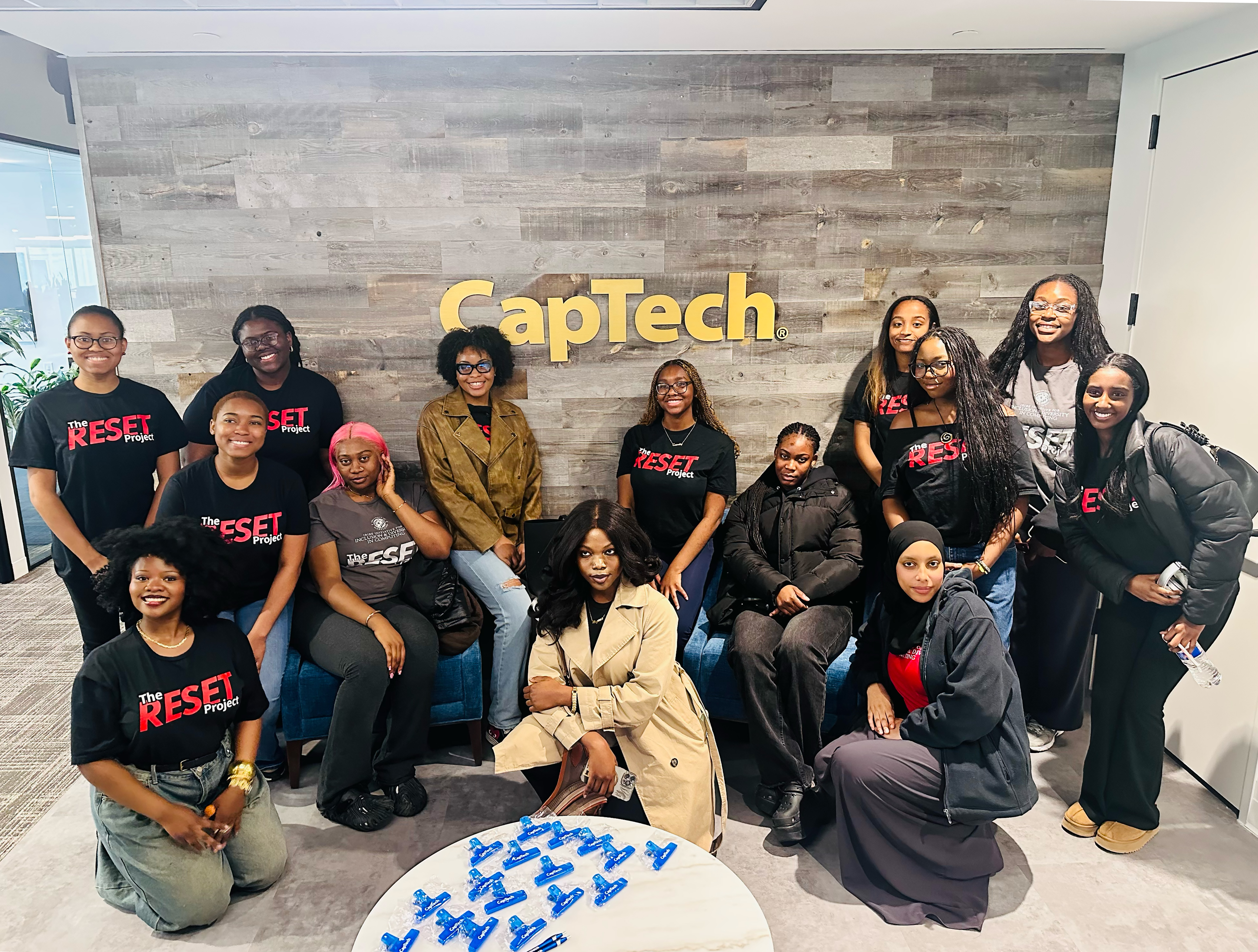 RESET Scholars pose as a group in front of a wall with the CapTech logo