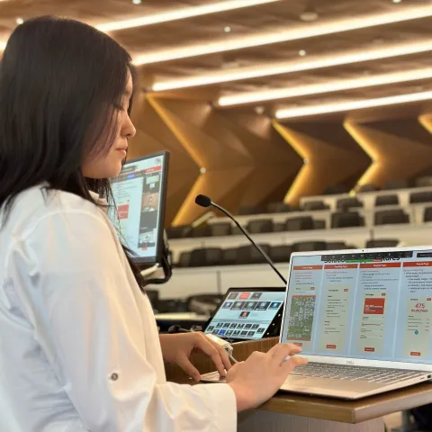 A woman standing behind a computer in front of a lecture hall