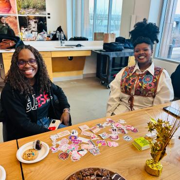 Two students sitting at a table and smiling at the camera