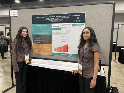 Two students standing on either side of a research poster