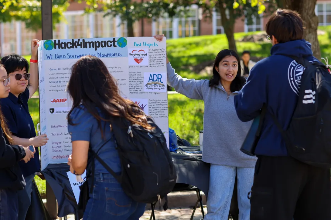 Students learn about Hack4Impact at an organization table.