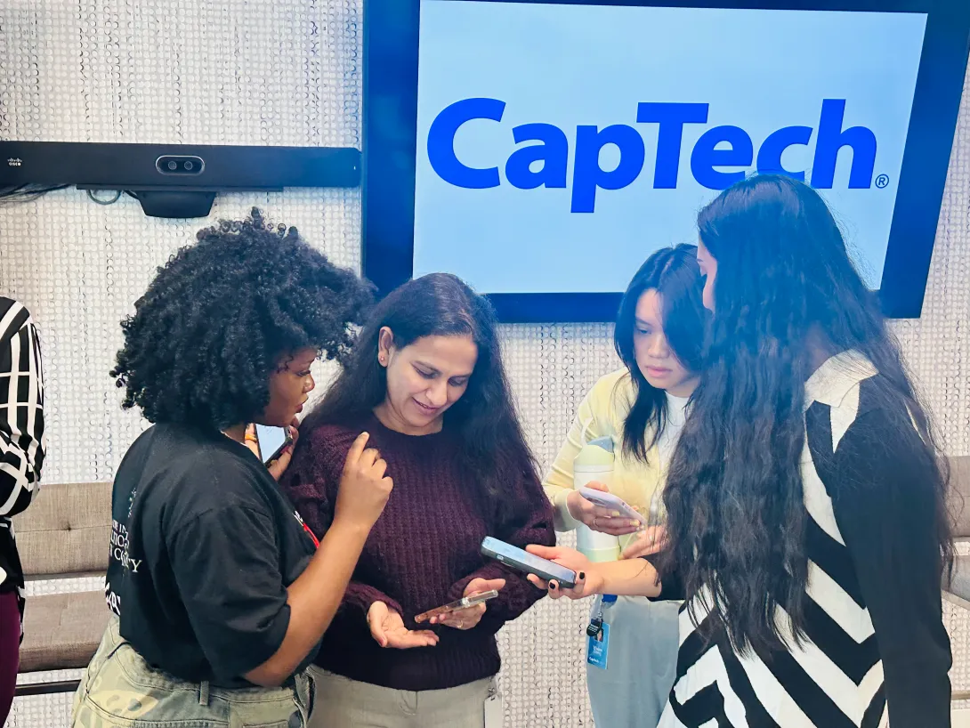 RESET Scholars and CapTech employees network in front of a screen with the CapTech logo