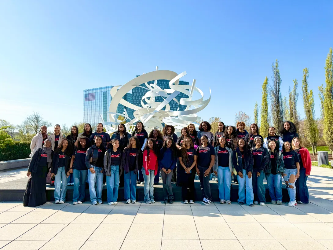 Group of students standing outside of EY's headquarters in Virginia in front of a large sculpture